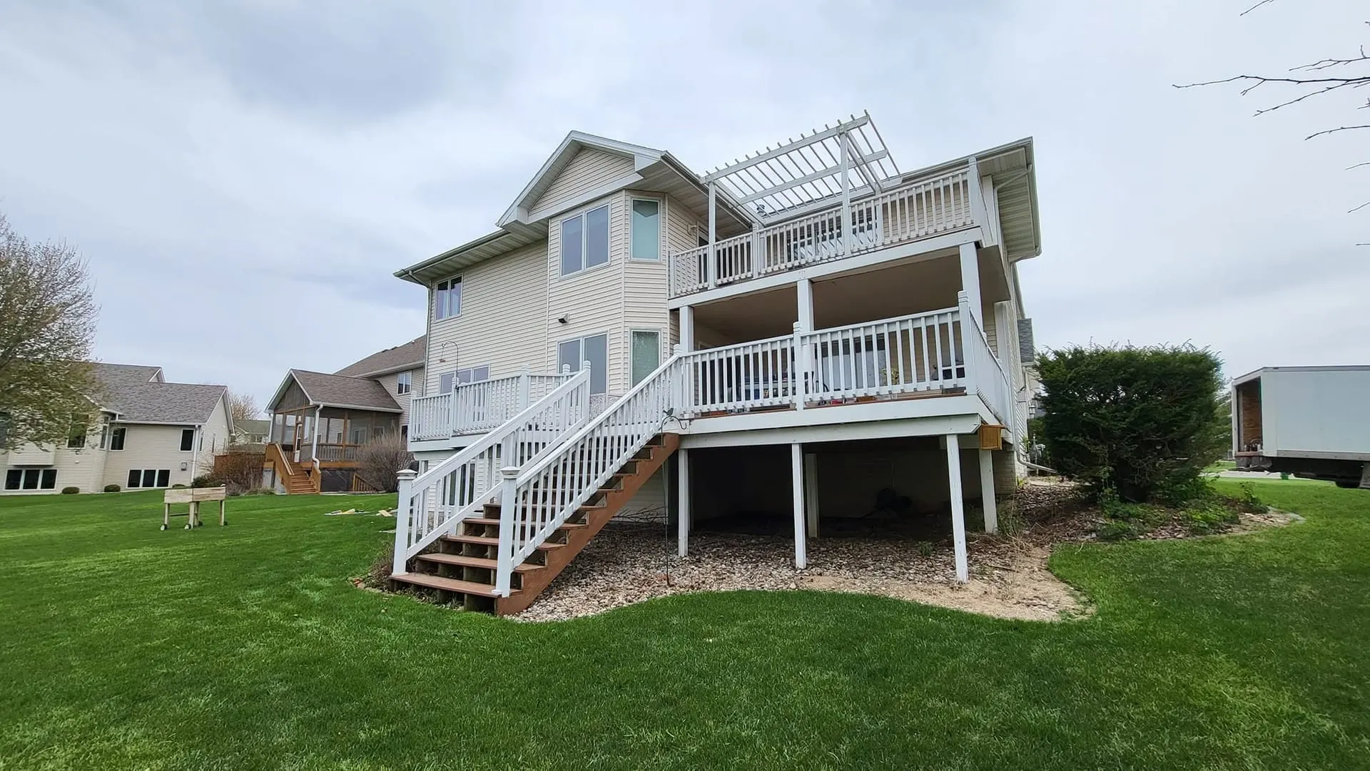 Back of a two-story home with tan siding and multiple new windows.