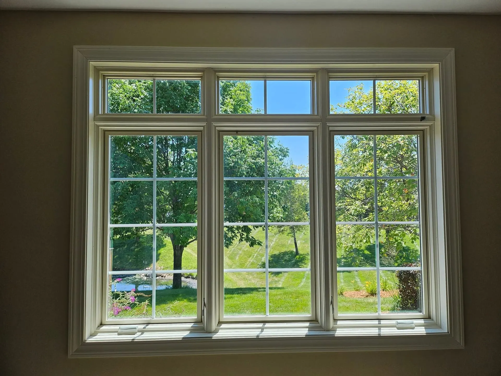 Interior view of a large triple-sash white window with transoms.